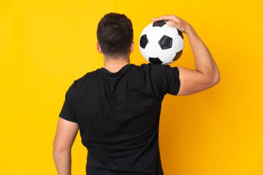 Futbol topuyla izole edilmiş sarı arka planda beyaz bir adam.