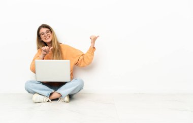 Dizüstü bilgisayarı olan genç bir kadın ürününü sunmak için yan tarafa bakıyor.