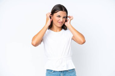 Beyaz arka planda izole edilmiş genç beyaz kadın hayal kırıklığına uğramış ve kulaklarını kapatmış.