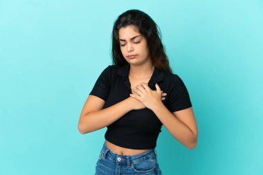 Mavi arka planda izole edilmiş beyaz bir kadın. Kalbinde ağrı var.