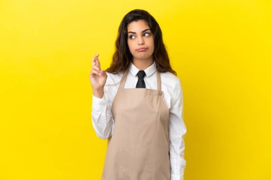 Kafkas restoranındaki genç garson sarı arka planda izole edilmiş ve şans diliyor.