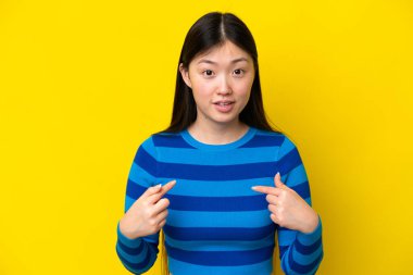 Sarı arka planda izole edilmiş genç bir Çinli kadın kendini işaret ediyor.