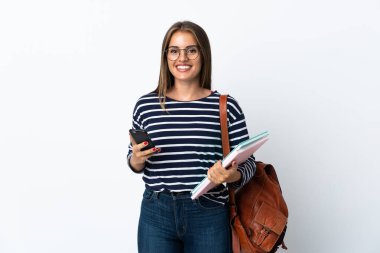 Beyaz arka planda izole edilmiş genç bir bayan elinde kahve ve bir cep telefonu var.