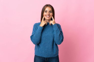 Genç Uruguaylı kadın pembe arka planda izole edilmiş mutlu ve hoş bir ifadeyle gülümsüyor.