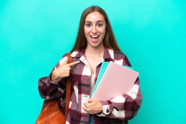 Mavi arka planda yüzü sürpriz bir ifadeyle izole edilmiş beyaz bir kadın öğrenci.