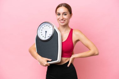 Pembe arka planda tartı makinesiyle izole edilmiş beyaz bir kadın.
