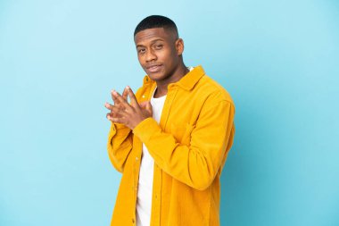 Genç latin adam mavi arka planda bir şeyler planlıyor.