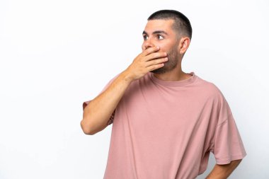 Beyaz arka planda izole edilmiş genç beyaz adam yan tarafa bakarken sürpriz jest yapıyor.