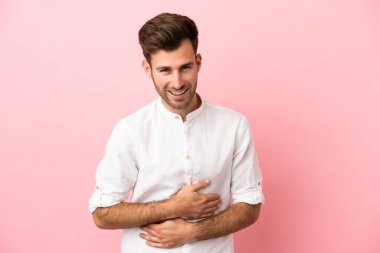 Beyaz tenli yakışıklı bir adam pembe arka planda izole edilmiş, sürekli gülümsüyor.