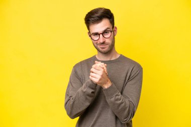 Sarı arka planda izole edilmiş genç beyaz adam gülüyor.