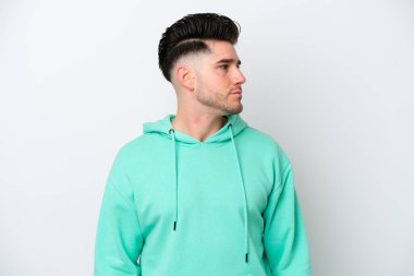 Beyaz arka planda izole edilmiş genç beyaz adam yan tarafa bakıyor.