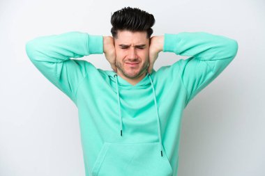 Beyaz arka planda izole edilmiş genç beyaz adam hayal kırıklığına uğramış ve kulaklarını kapatmış.