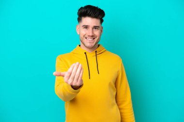 Kafkasyalı genç bir adam mavi arka planda izole edilmiş ve davet edilmişti. Gelmene sevindim.