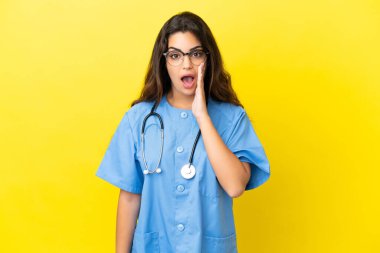 Sarı arka planda, şaşırmış ve şok olmuş bir yüz ifadesiyle izole edilmiş genç cerrah kadın.