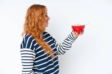 Beyaz arka planda kahvaltı sütü içen beyaz bir kadın. Mutlu bir ifadeyle.