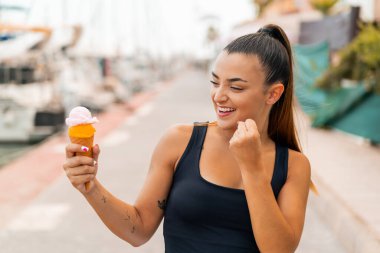 Açık havada kornet dondurmalı genç ve güzel bir kadın zaferi kutluyor.