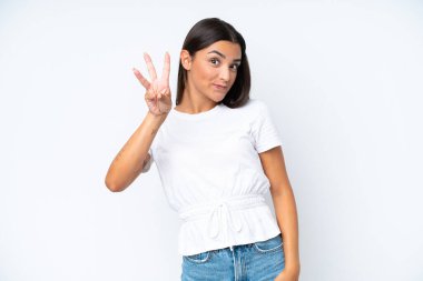 Beyaz arka planda izole edilmiş beyaz kadın mutlu ve parmaklarıyla üçe kadar sayıyor.