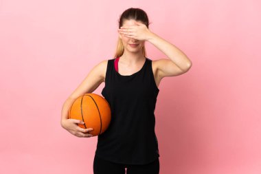Basketbol oynayan genç sarışın kadın pembe arka planda izole edilmiş gözlerini elleriyle kapatıyor. Bir şey görmek istemiyorum.