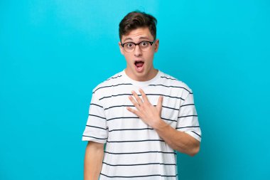 Young handsome Brazilian man isolated on blue background surprised and shocked while looking right