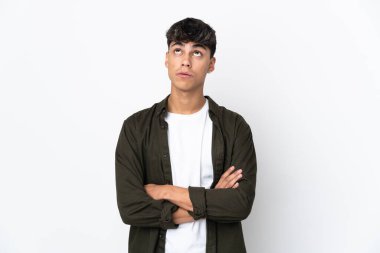 İzole edilmiş beyaz arka planda genç bir adam yukarı bakıyor ve şaşırmış bir ifadeyle