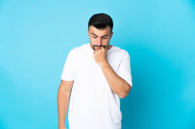 İzole edilmiş mavi arka planda beyaz bir adamın şüpheleri var.