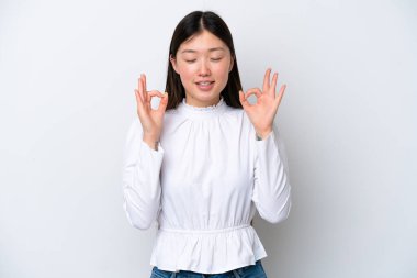 Zen pozunda beyaz arka planda izole edilmiş genç Çinli kadın.