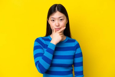 Sarı arka planda izole edilmiş genç bir Çinli kadın.