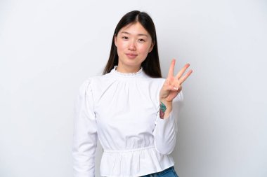 Beyaz arka planda izole edilmiş genç Çinli kadın mutlu ve parmaklarıyla üçe kadar sayıyor.