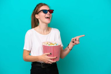 Mavi arka planda 3 boyutlu gözlüklü ve elinde koca bir kova patlamış mısırla dolaşan genç bir İngiliz kadın.