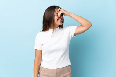 Genç Uruguaylı kadın mavi arka planda izole edilmiş, gülümsüyor.