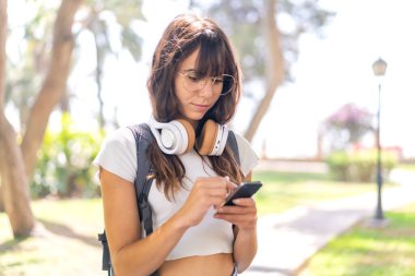 Açık havada cep telefonu kullanan genç bir kadın.