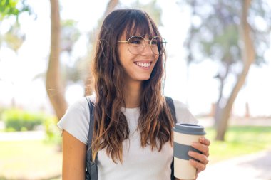 Açık havada elinde kahve tutan genç bir kadın.