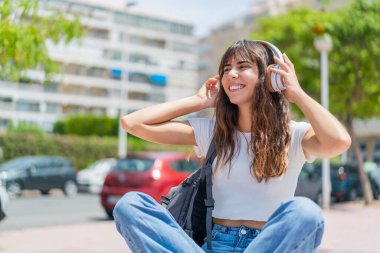 Açık havada müzik dinleyen genç bir kadın