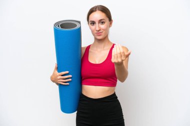 Beyaz arka planda izole edilmiş bir paspası tutarak yoga derslerine giden beyaz, sporcu bir kadın. Gelmene sevindim.
