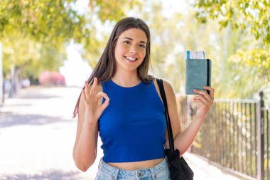 Dışarıda pasaport tutan genç, güzel Brezilyalı kadın parmaklarıyla 