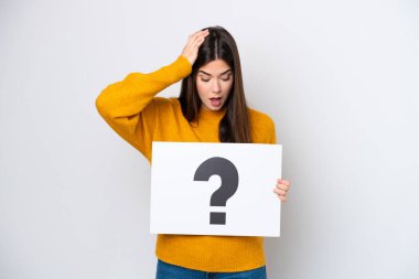 Beyaz arka planda izole edilmiş genç Brezilyalı bir kadın soru işareti sembollü bir levha tutuyor ve şaşırmış bir ifade var.