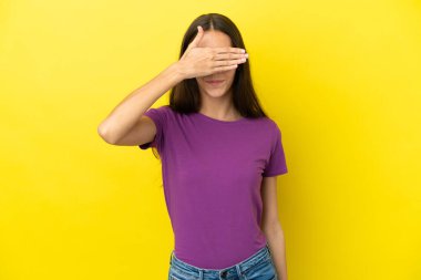 Sarı arka planda izole edilmiş genç bir Fransız kadın gözleri elleriyle kapatıyor. Bir şey görmek istemiyorum.
