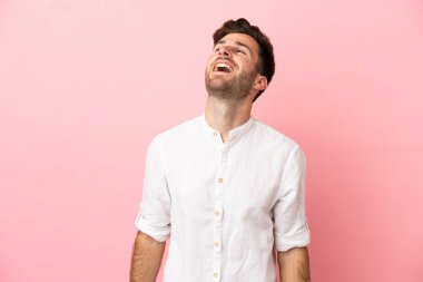 Beyaz tenli yakışıklı adam pembe arka planda izole edilmiş gülüyor.