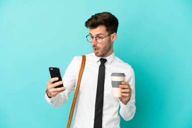 İş adamı izole edilmiş arka planda kahve ve cep telefonu tutuyor.