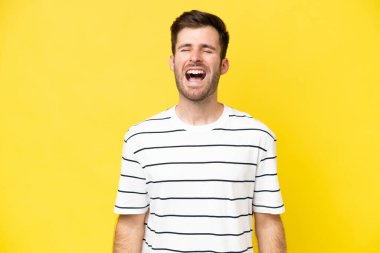 Sarı arka planda izole edilmiş genç beyaz bir adam ağzı açık bir şekilde öne doğru bağırıyor.