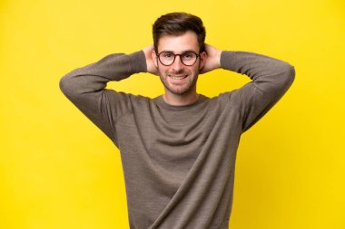 Sarı arka planda izole edilmiş genç beyaz adam gülüyor.