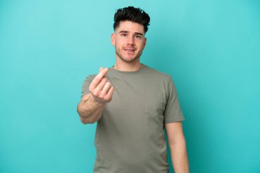 Mavi arka planda izole genç beyaz adam para jesti yapıyor