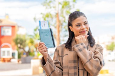 Pasaportu elinde tutan genç ve güzel bir kadın bir fikir üretiyor ve etrafa bakıyor.
