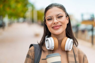 Genç, güzel bir kadın açık havada, mutlu bir ifadeyle.