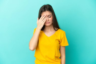 Kafkasyalı genç bir kadın mavi arka planda izole edilmiş, baş ağrısı var.