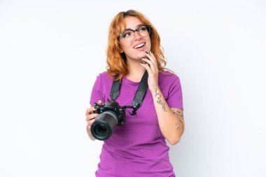 Beyaz arka planda izole edilmiş genç fotoğrafçı kadın gülümserken yukarı bakıyor.