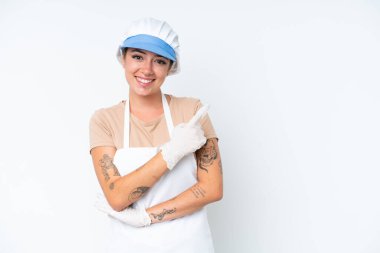 Balıkçı önlük takıyor ve beyaz arka planda izole edilmiş çiğ bir balık tutuyor.