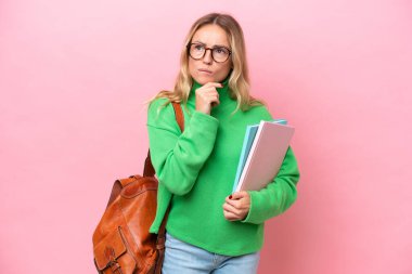 Pembe arka planda izole edilmiş genç bir kadın şüpheleri ve düşünceleri var.