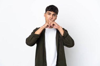 İzole edilmiş beyaz arka planda genç bir adam sessizlik işareti gösteriyor.