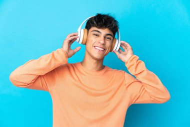 Soyutlanmış mavi arka plan müzik dinleyen genç adam.